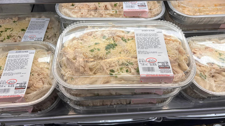 A row of premade packages of Kirkland Signature chicken alfredo rest in a fridge at Costco.