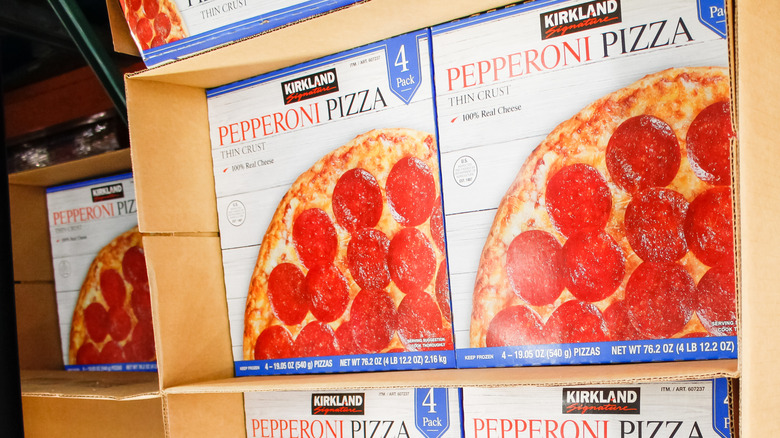 A row of Kirkland signature pepperoni pizza boxes sit in a Costco aisle.