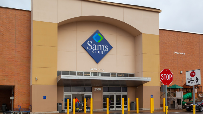 Outside of a Sam's Club, showing the blue and white logo on a cream background over the entrance doors