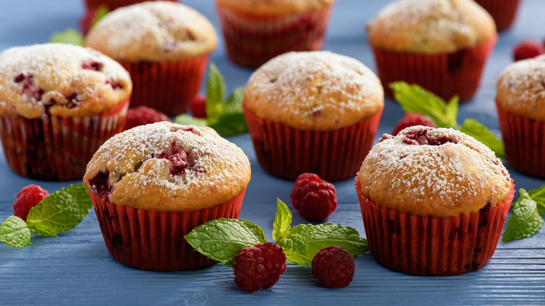 Raspberry muffins with greens and raspberries on a blue table