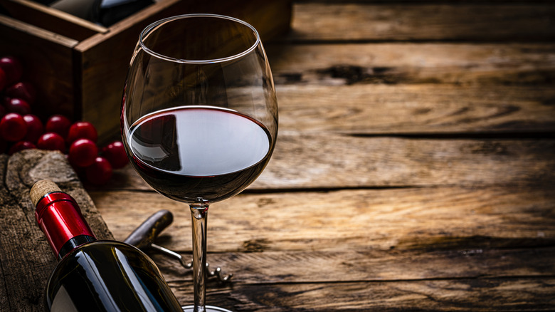 Glass of red wine on a rustic wooden table.