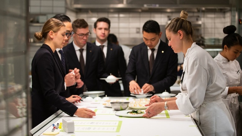Sous chef preps a plate in front of the front of house team at Per Se
