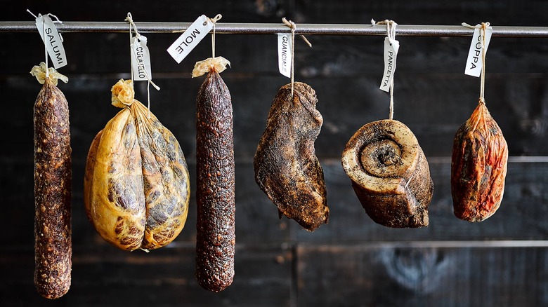 Cured meats drying on a pole at Salumi