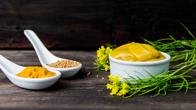 Mustard sauce, seeds, and powder on a wooden surface