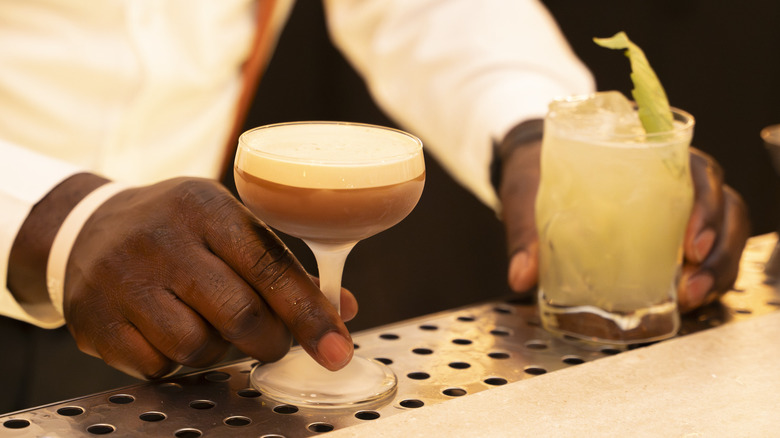Elegant bartender serves two cocktails