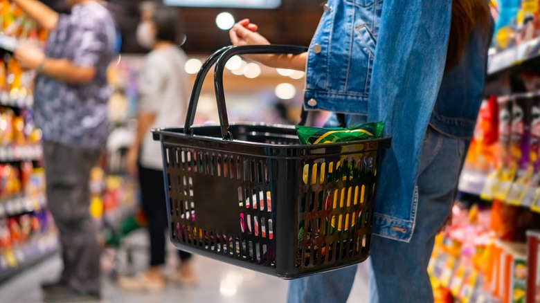 A grocery store customer carrying a basket