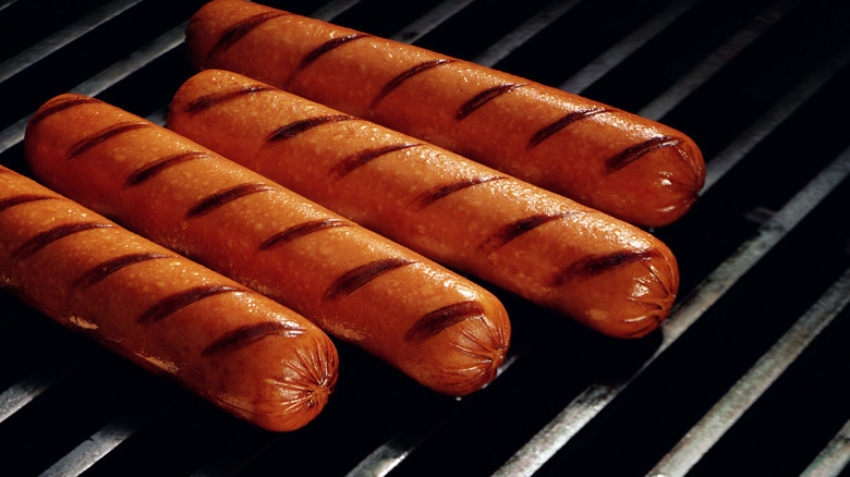 Hot dogs on grill with grill marks seared into them.