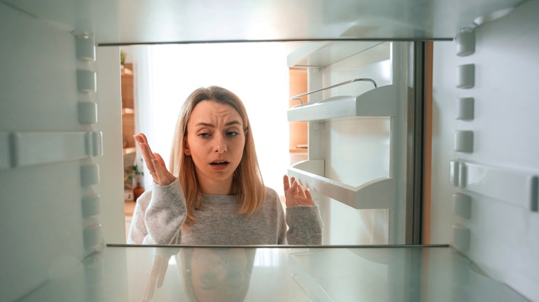 Person looking disappointed at the inside of a fridge