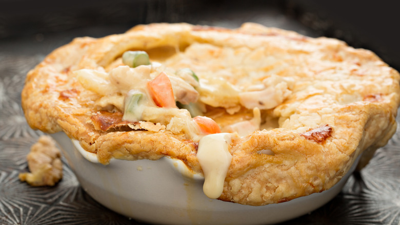 Close-up of a pot pie with the crust broken to reveal the filling