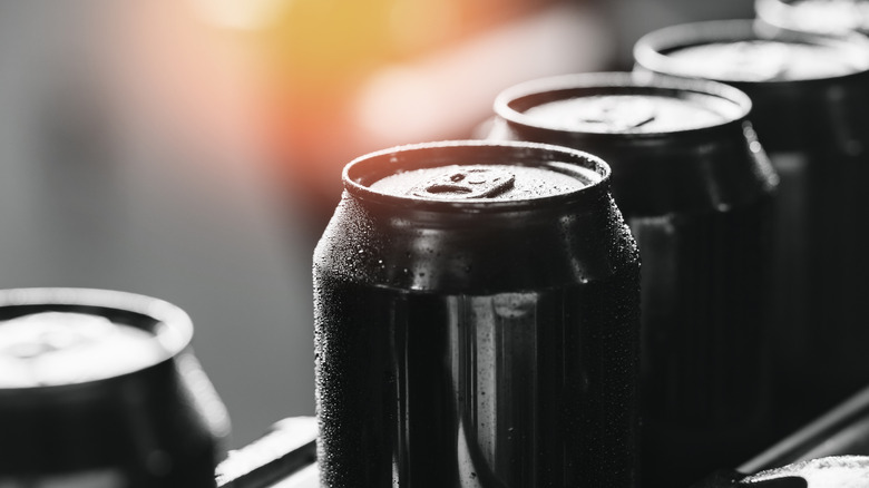 A closeup of black and white beer cans witch yellow sunlight behind them