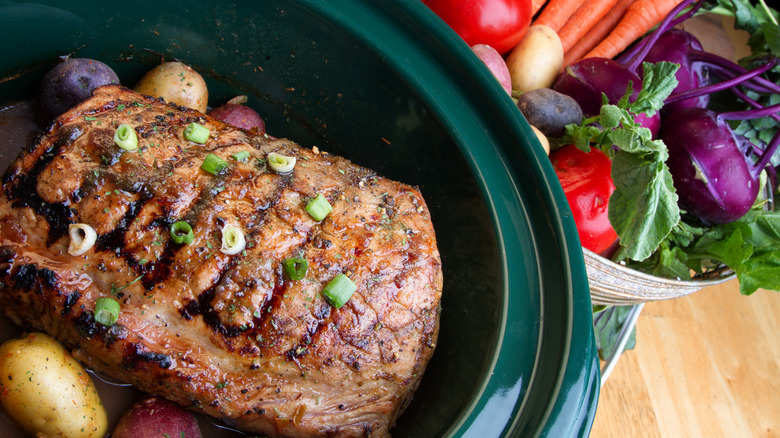 Top view of seared beef roast and potatoes in slow cooker