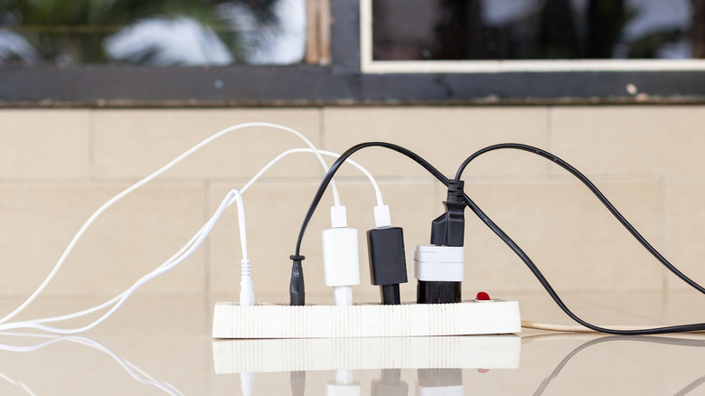 Close-up of an overloaded power strip with multiple plugs and tangled wires.
