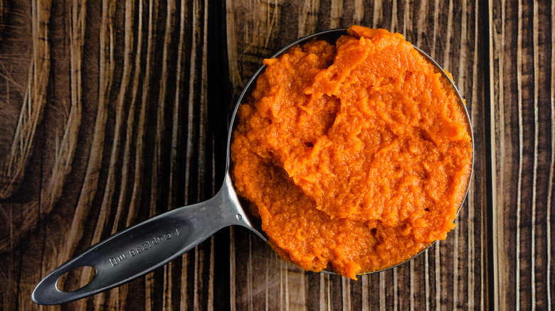 Top view of a metal measuring cup filled with pumpkin puree