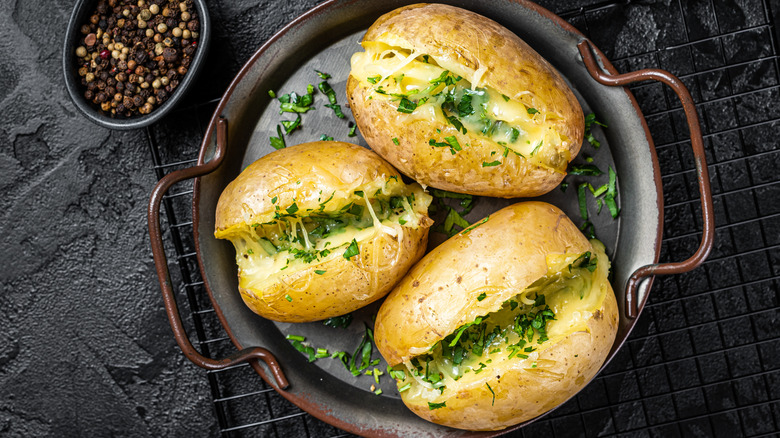 Three baked potatoes stuffed with butter, herbs, and cheese