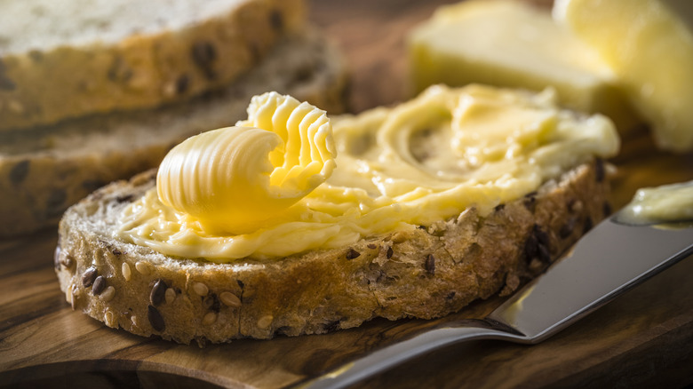 A slice of bread spread with butter with a butter curl on top.