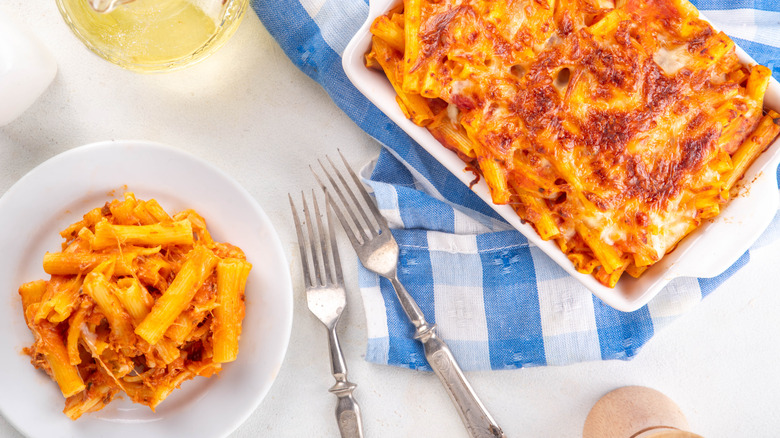 Top view of baking dish and plate of baked ziti pasta