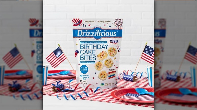 A bag of Drizzilicious 250th﻿ Anniversary Birthday Cake Bites on a red checked tablecloth with patriotically themed place settings and paper flags