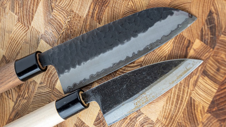 Two carbon Damascus steel knives on a wood board