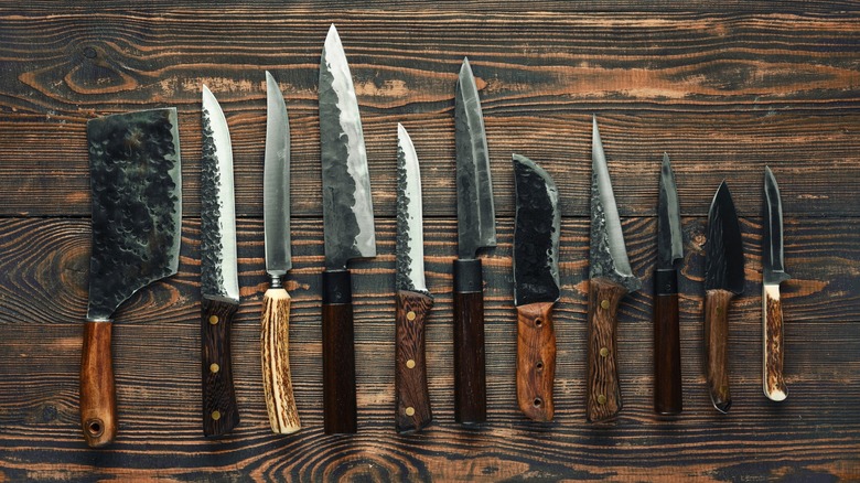 Various kitchen knives neatly arranged on a rustic wooden table