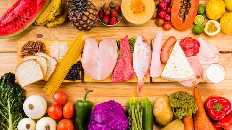 Various meats, vegetables, and fruits on wood table