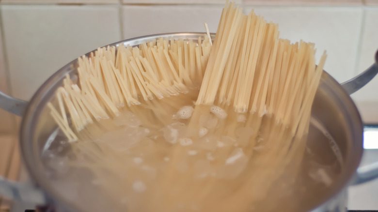 Spaghetti cooking in a large stock pot full of boiling water on a stove