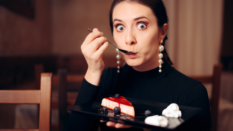 Woman with surprised look on her face as she eats cheesecake