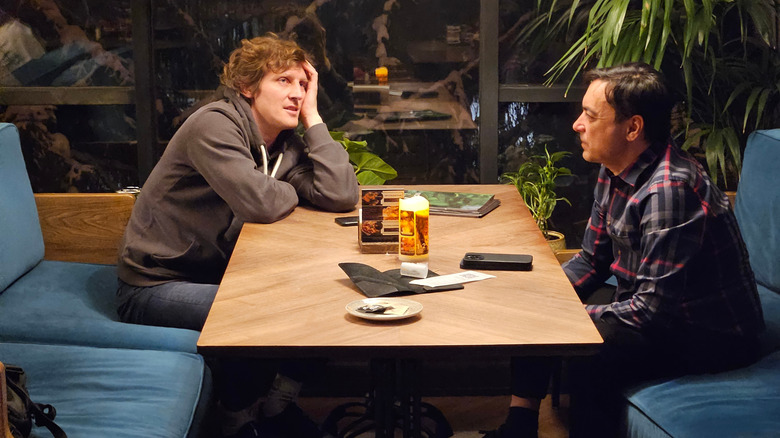 Two men sitting across from each other at a restaurant booth talking