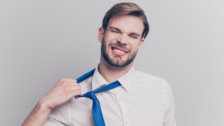 young man yanking off formal tie