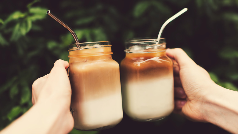 People clinking cold brew lattes in jars with metal straws