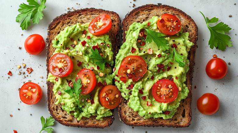 Toast topped with avocado, tomatoes and chilli flakes sitting on a counter