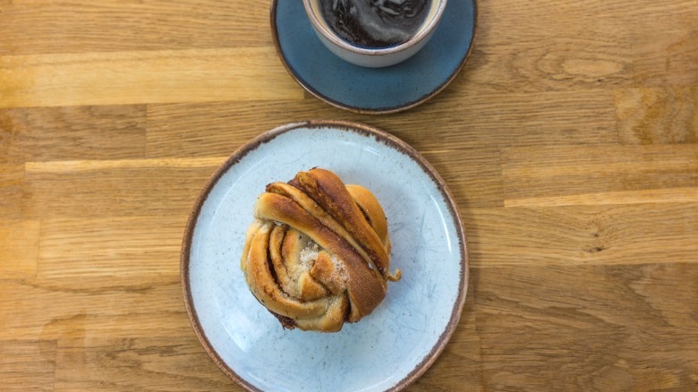A Norwegian kanelsnurre on a plate with a cup of coffee.