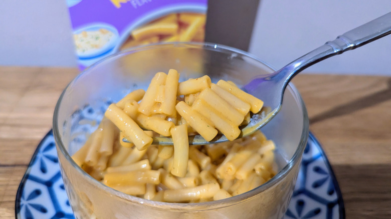 Forkful of chicken ramen-flavored Kraft Mac and Cheese with the box in background.