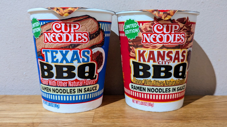 Two cup noodle cups on countertop in their original packaging.
