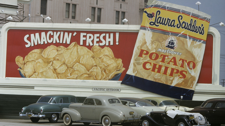 Vintage billboard advertising Laura Scudder's Potato chips near parking lot with vintage cars