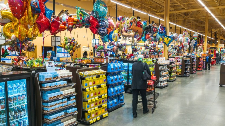 Person walking shopping cart past Wegmans checkout lanes