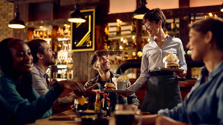 A member of the wait staff serving a group of friends at a restaurant