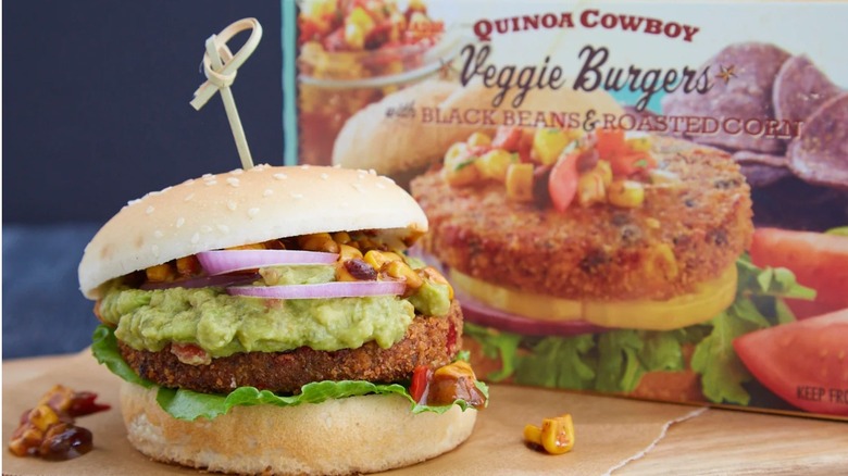 Trader Joe's Quinoa Cowboy Veggie Burger with Black Beans and Corn pictured as a burger with guacamole and burger package in the background