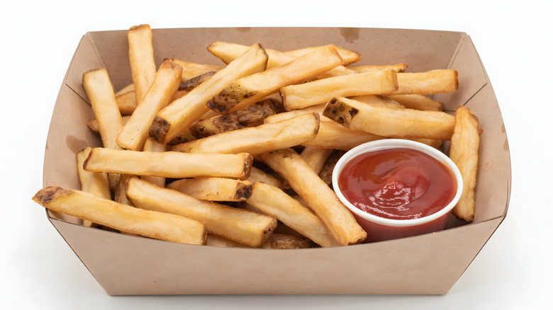 A basket of bland-looking french fries with ketchup.