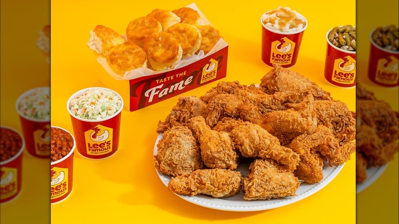 Large platter of fried chicken alongside a box of biscuits and various sides from Lee's Famous Recipe Chicken