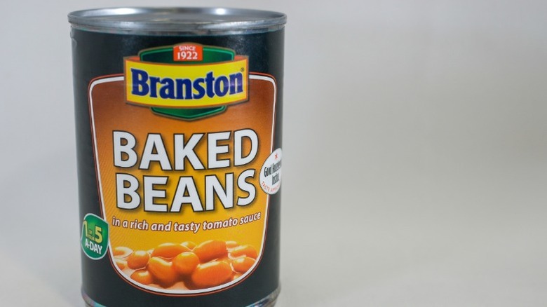 A can of Branston baked beans against a grey background.