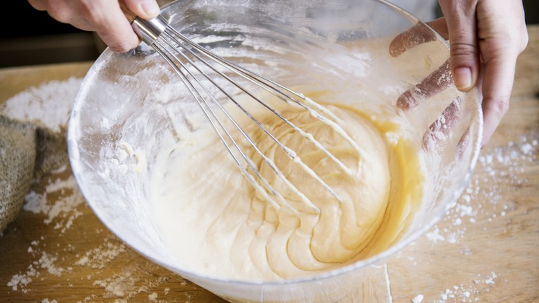 Person stirring cake mix in glass bowl