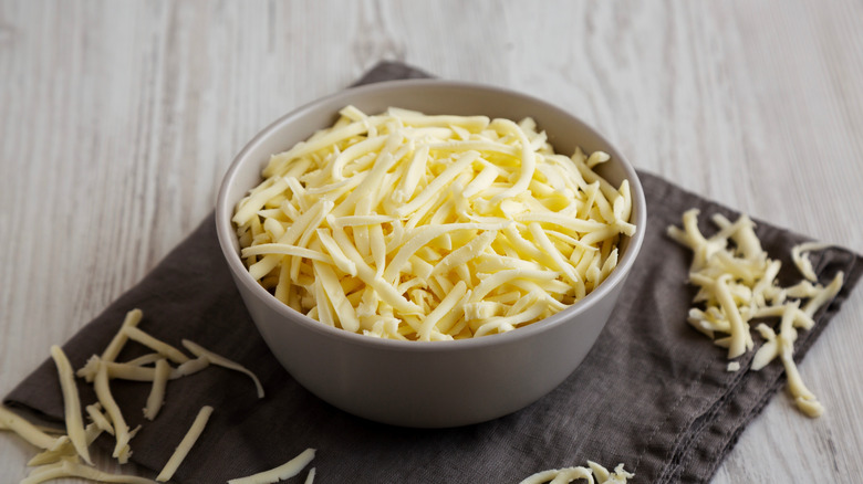 Shredded mozzarella in bowl resting on top of a napkin.