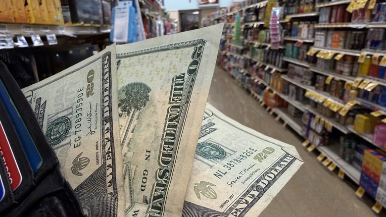 Wallet with three twenty dollar bills exposed in grocery store