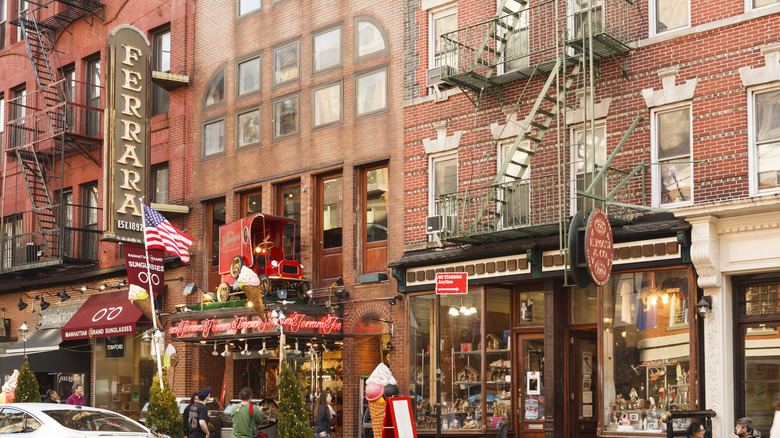 Cafe Ferrara in New York City with the sign hanging out in front of brick buildings.