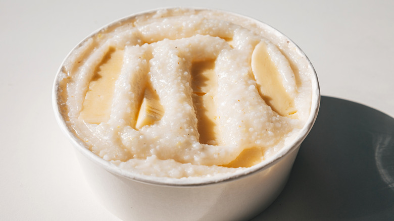 A white bowl of grits topped with slices of butter