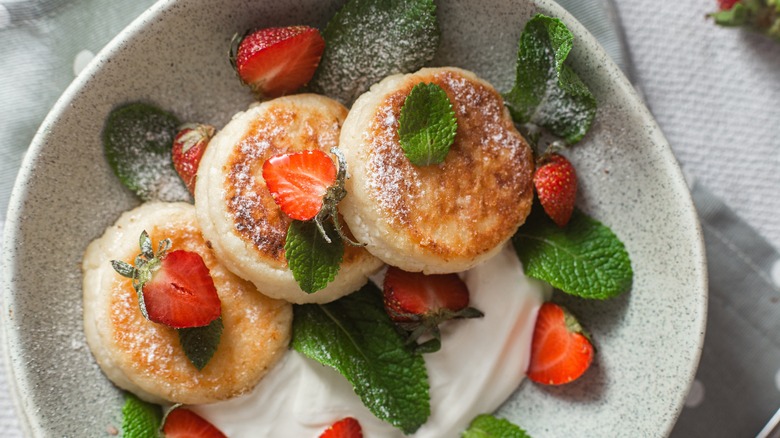 plate of cottage cheese pancakes with strawberries, mint, and whipped cream
