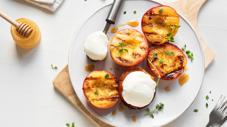 Top view of grilled peaches with honey ice cream and fresh herbs