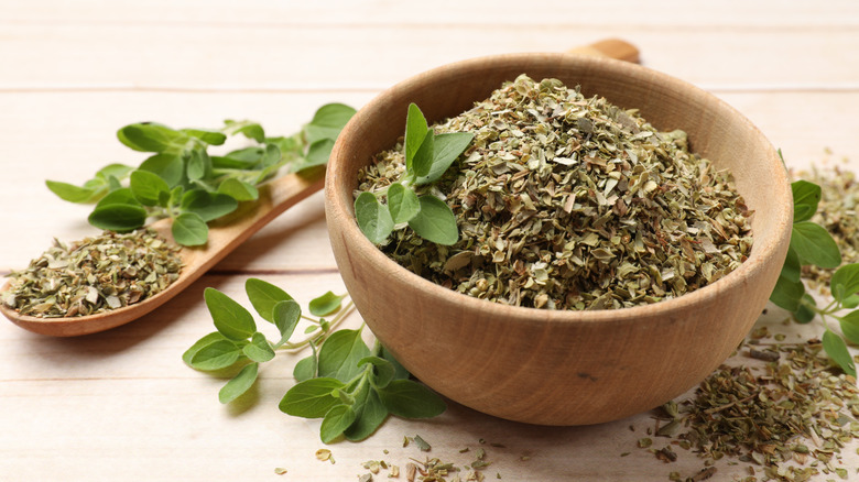 Dried oregano in a small wooden bowl with fresh organo leaves