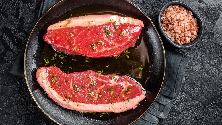 top-down view of two slabs of steak coated in olive oil, salt, and thyme.