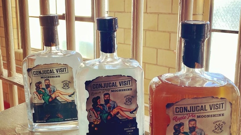 Bottles of Conjugal Visit Moonshine in front of barred windows at Boone County Jail distillery